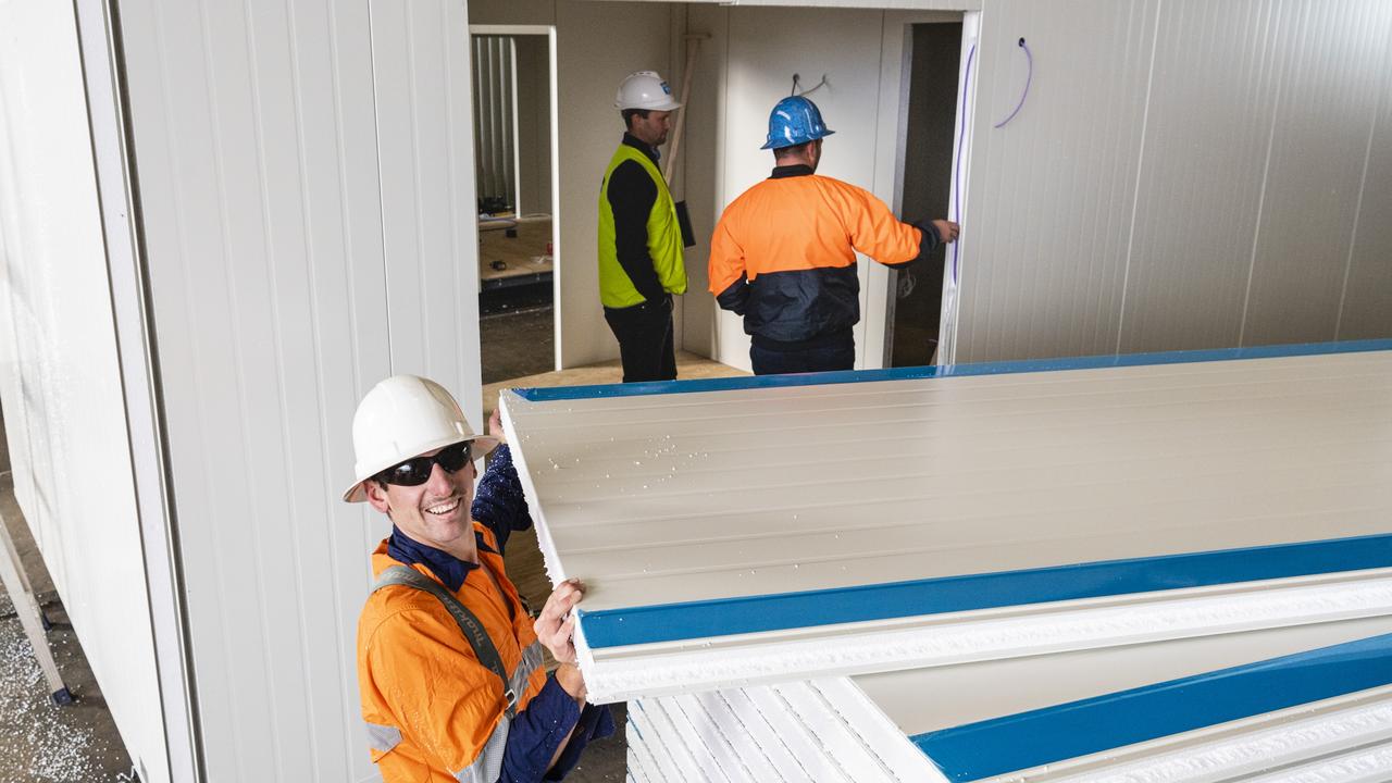 Tom Cauley (front) with a panel as Hutchinson Builders in Toowoomba construct modular housing to support flood victims in Lismore. Picture: Kevin Farmer