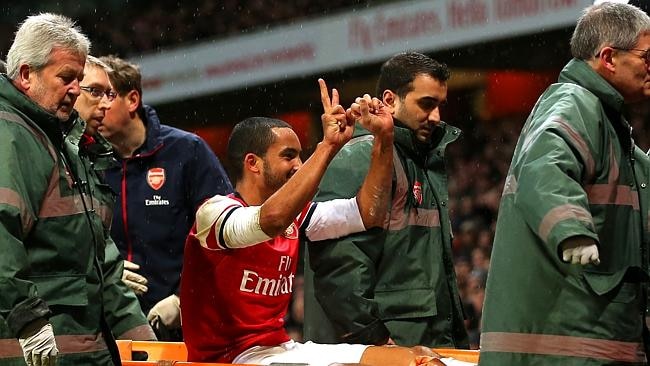 The injured Theo Walcott of Arsenal makes a 2-0 gesture to the Tottenham fans as he is stretchered off the pitch during the B...