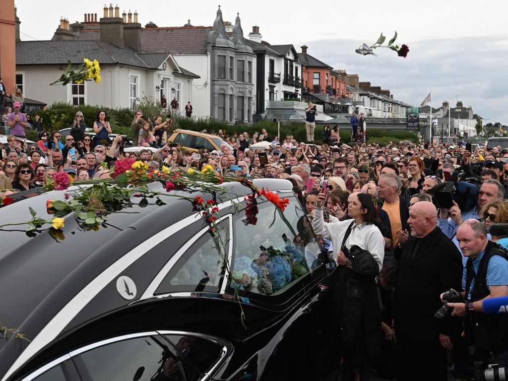 Crowds lining the streets throw flowers as the hearse carrying Sinead O'Connor's coffin passes by her former home on the seafront in Bray, Ireland. Picture: Charles McQuillan/Getty Images