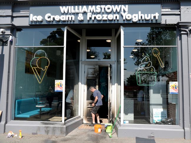 Workers repairing a fire damaged door at the Williamstown ice creamery. Picture: Andrew Henshaw