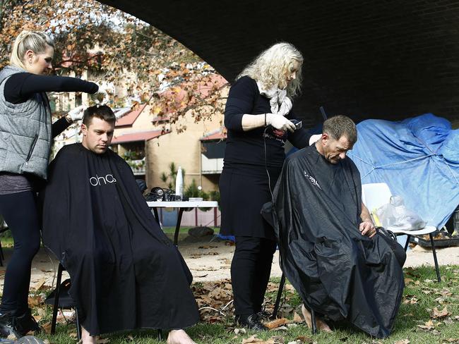 L to R: Lyndle Dryan and Beth Shannon from hair on the move cut hair for "Gary " and Dylan McDonald  at Wentworth Park. C3 Church Rozelle has been helping the homeless in Wentworth Park for the past 12 months and arranged for mobile hairdressers to come and do haircuts for the homeless. Picture: John Appleyard