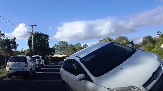 The Ford Focus on its side as it passes police during the alleged dangerous driving incident at Jones Hill, in the Gympie region