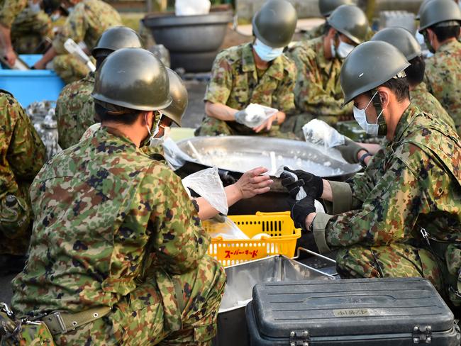 Members of the Japan Self-Defense Forces make rice balls at an evacuation centre in Mashiki. Picture: Masterpress.