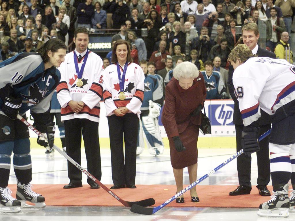 Queen Elizabeth II drops the puck during the ceremonial face-off between Markus Naslund of the Vancouver Canucks and Mike Ricci of the San Jose Sharks in 2002.