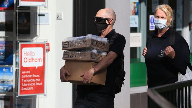 Pedestrians wearing a face masks commute through Oldham, near Manchester, England. Picture: AFP