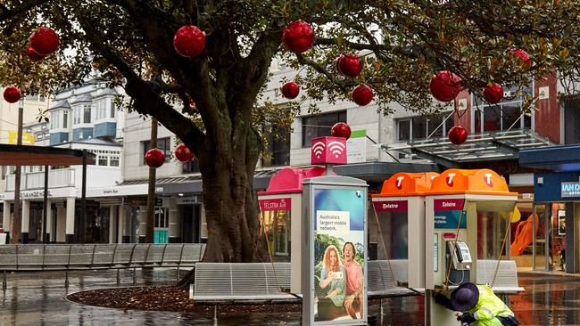 A contractor cleans public telephones in the Manly Corso on December 19 as a cluster of COVID-19 cases on the northern beaches of Sydney continues to grow. Picture: Getty