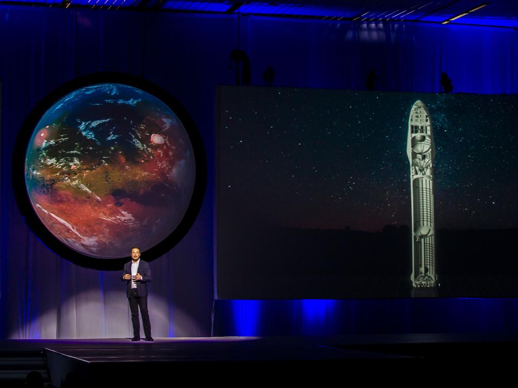 Green Mars … Tesla Motors CEO Elon Musk standing in front of an image of a Mars with oceans and green fields. Picture: AFP