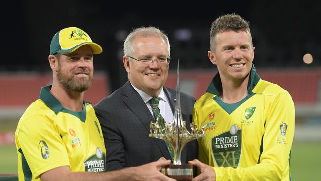 Scott Morrison holds the trophy with Prime Minister’s XI co-captains Dan Christian and Peter Siddle in October 2019. Photo by Tracey Nearmy/Getty Images