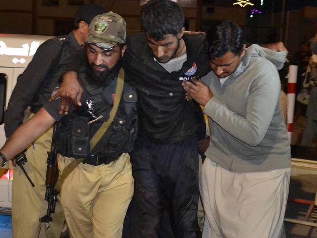 A Pakistani volunteer and a police officer rush an injured person to a hospital in Quetta, Pakistan, Monday, Oct. 24, 2016, after two separate attacks in Pakistan. Gunmen stormed a police training center in the restive southwestern province of Baluchistan Monday, leaving several people wounded, hours after another attack near to Quetta leaving two customs officers dead, authorities said. (AP Photo/Arshad Butt)
