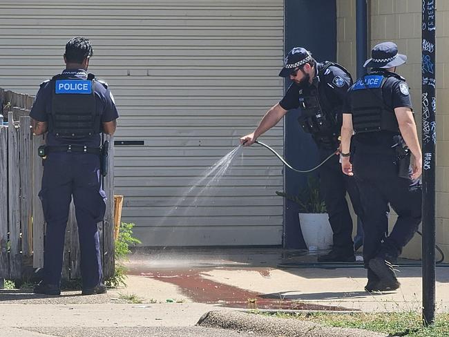 Police hose blood off the driveway of a Garbutt residence after a woman had her arm severed by a dog.