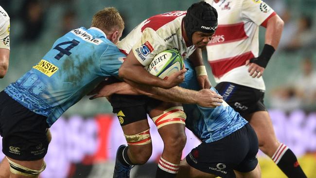 The Lions’ Marvin Orie is tackled by Waratahs players Tom Staniforth (left) and Michael Hooper on Friday night.