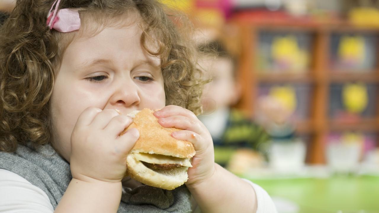 A young girl eating a hamburger, which has a lot of calories. Picture: iStock