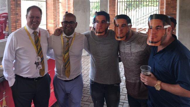 South African cricket officials Clive Eksteen (left) and Altaaf Kazi (second from left) pose with fans wearing Sonny Bill Williams masks, a slur against David Warner's wife Candice.