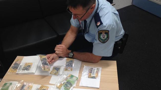 Inspector Jim Szabo with a number of fake counterfeit $50 and $100 notes