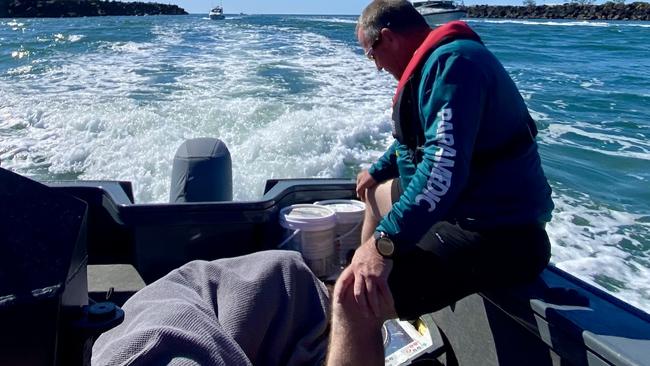 Paramedics bring the injured boatie, covered by a blanket, to shore. Picture: Supplied