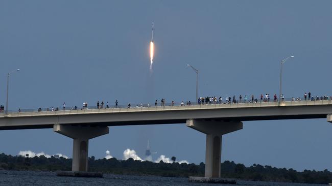 People line the A.Max Brewer Causeway to watch the launch of a SpaceX Falcon 9 rocket.