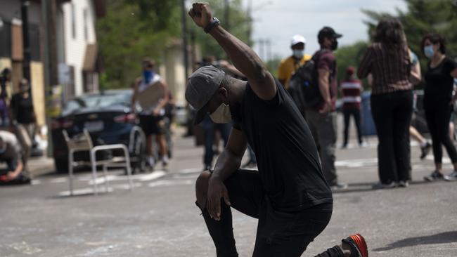 A man kneels and holds up his fist at a memorial site where George Floyd died. Picture: AFP