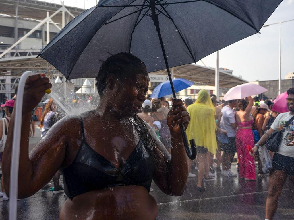 Fans cool off in a heatwave while lining up for Taylor Swift’s concert in Rio de Janeiro, where organisers later apologised for insufficient safety measures after a fan’s death. Picture: Tercio Teixeira/AFP