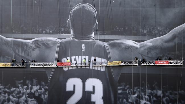 Workmen finish hanging a 10-story-tall Nike banner with LeBron James likeness on a building in Cleveland.