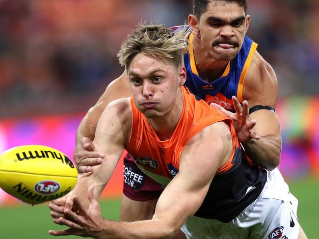 Giants Jackson Hatley handballs ahead of Brisbane's Charlie Cameron during the AFL match between the GWS Giants and Brisbane Lions at Giants Stadium. Picture. Phil Hillyard