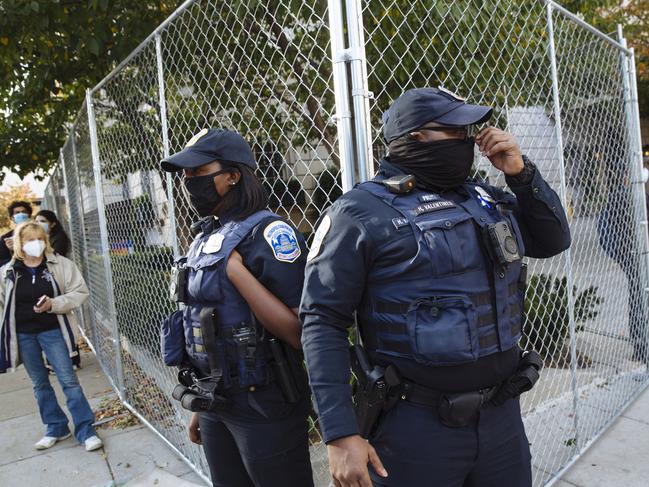 Police stand along a fence near the White House.