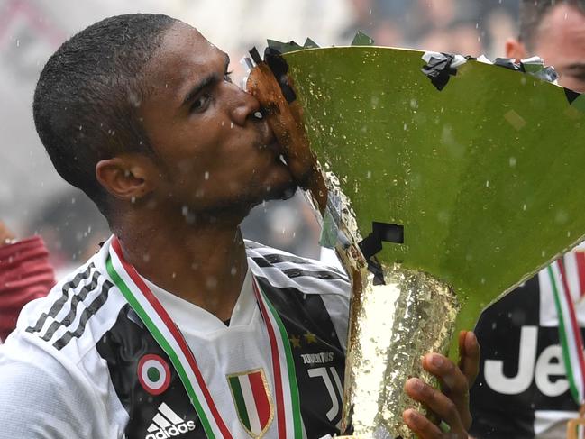 Juventus' forward from Brazil Douglas Costa kisses the trophy during the victory ceremony following the Italian Serie A last football match of the season Juventus versus Verona, on May 19, 2018 at the Allianz Stadium in Turin. Juventus won their 34th Serie A title (scudetto) and seventh in succession.  Italy great Gianluigi Buffon played his last game with Juventus today after 17-year with the Serie A champions. / AFP PHOTO / Andreas SOLARO