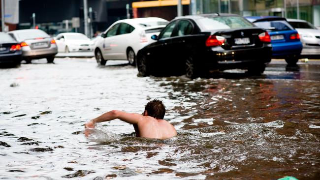 A man swims along Elizabeth St during 2010 flooding