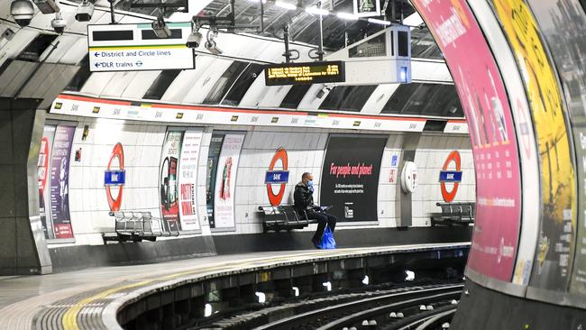 A man wearing a protective face mask waits for a Central Line underground train on an empty platform at Bank Station, in London.