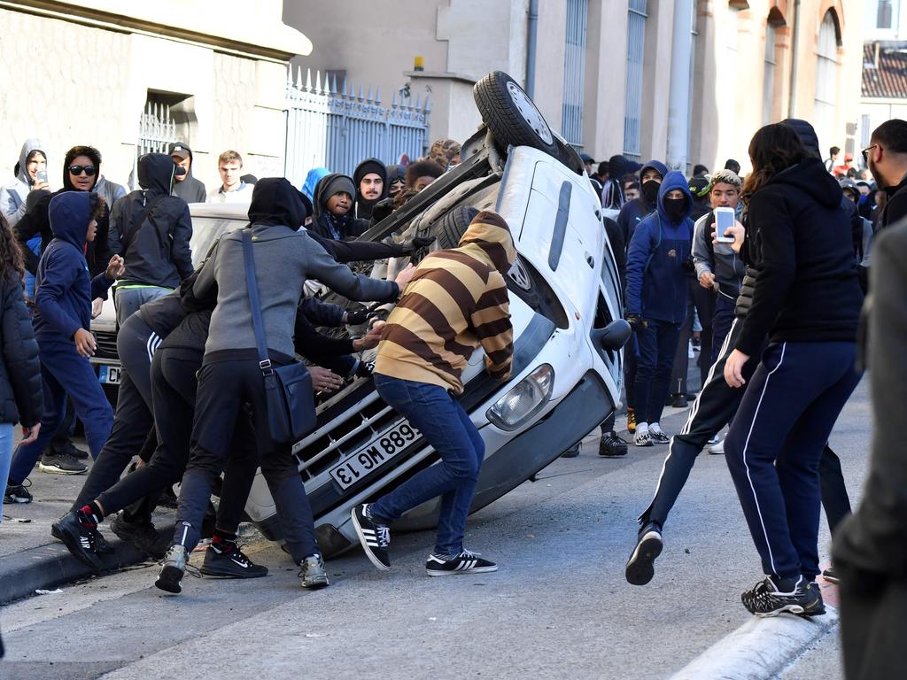 Protesters overturn a vehicle on December 6 in Marseilles, during a demonstration of high school students protesting against French government education reforms. Picture: Gerard Julien/AFP