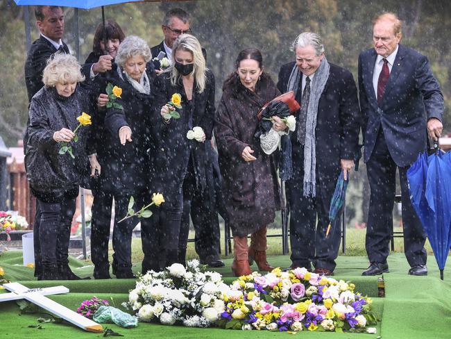 Patti Newton, daughter Lauren, and family and friends throw roses onto Bert’s coffin at Springvale Cemetery. Picture: David Caird