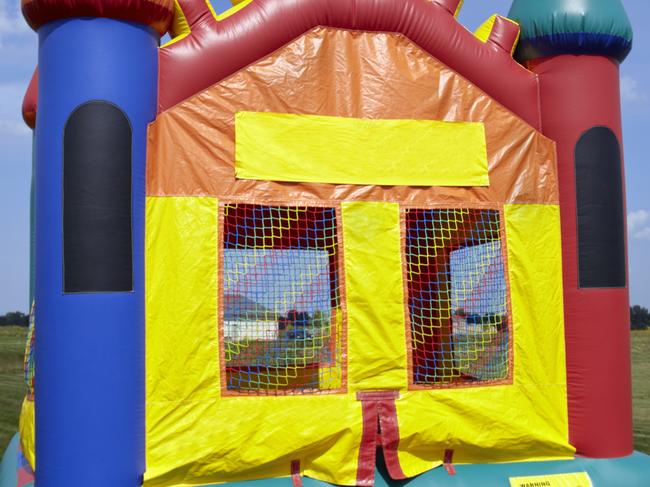 Stock photo of a children's bouncy castle inflatable jumper playground in a grass field with a blue sky.