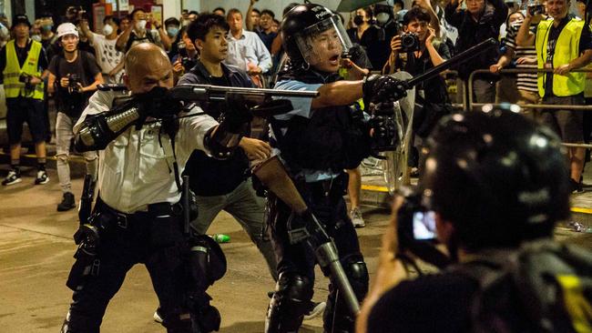 A police officer (C) points a firearm during clashes with protesters who had gathered outside Kwai Chung police station, in support of protesters detained with the charge of rioting, in Hong Kong on July 30, 2019. (Photo by ISAAC LAWRENCE / AFP)