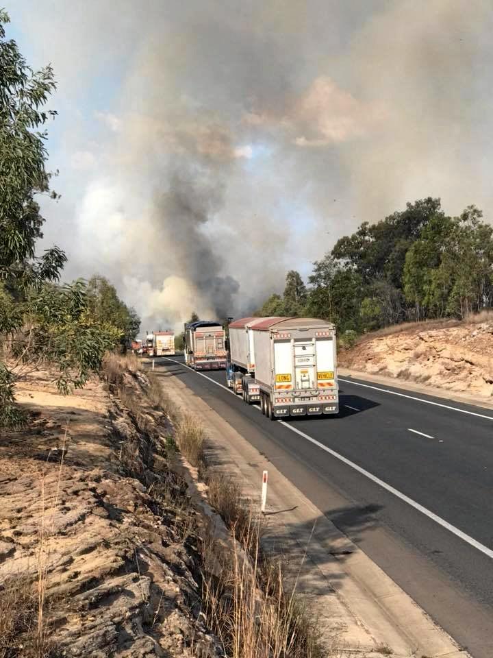 Trucks line up along the Warrego Highway as a fire burns out of control at Grantham. Picture: Clinton Williams