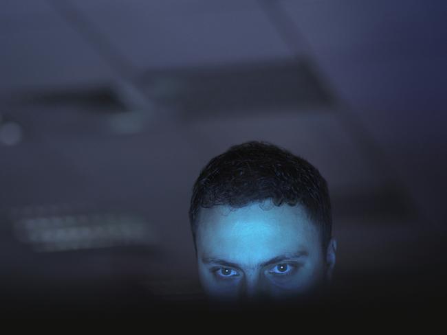 Computer hacker working on laptop late at night in office