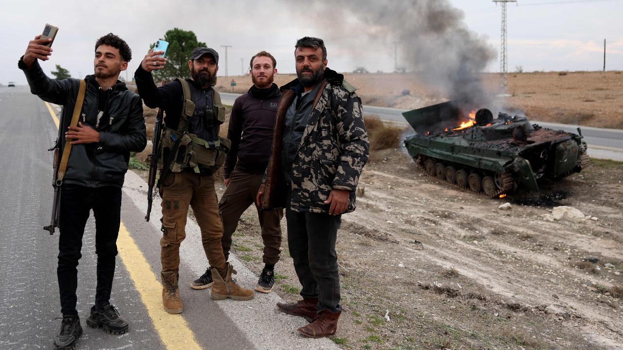 Armed men pose for pictures near a military vehicle belonging to the Syrian regime forces and seized by anti government forces. Picture: Omar Haj Kadour/AFP