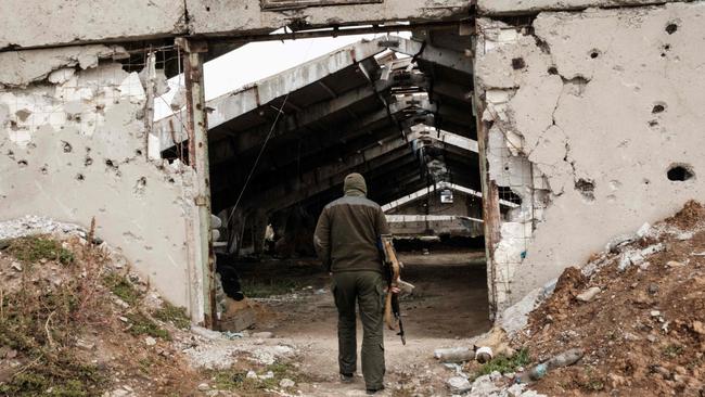 An unidentified Ukrainian soldier enters a destroyed building at an industrial chicken farm, near which the Russian forces were dug in, near a suspected mass grave in Kozacha Lopan, Kharkiv region.