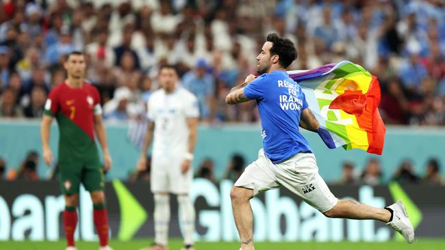 LUSAIL CITY, QATAR – NOVEMBER 28: A pitch invader wearing a shirt reading "Respect for Iranian woman" holds a rainbow flag during the FIFA World Cup Qatar 2022 Group H match between Portugal and Uruguay at Lusail Stadium on November 28, 2022 in Lusail City, Qatar. (Photo by Francois Nel/Getty Images)