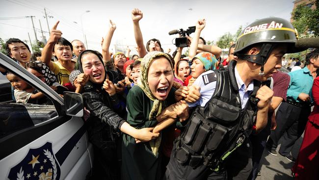 Ethnic Uygur women grab a riot policemen as they protest in Urumqi in China's far west. Picture: Peter Parks/AFP