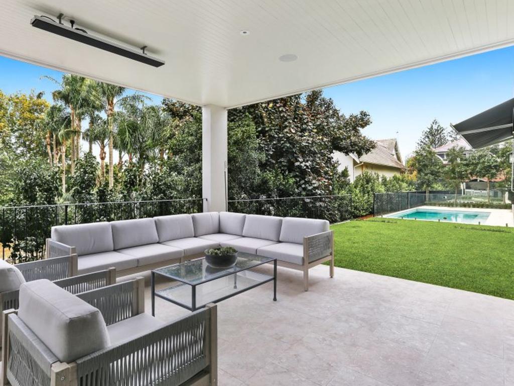 An undercover outdoor entertainment area opens to a level lawn and the pool.