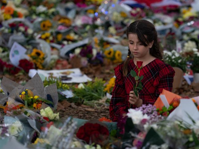 A young girl holds a rose as she looks at flowers laid in Green Park in memory of Queen Elizabeth II. Picture: Getty.