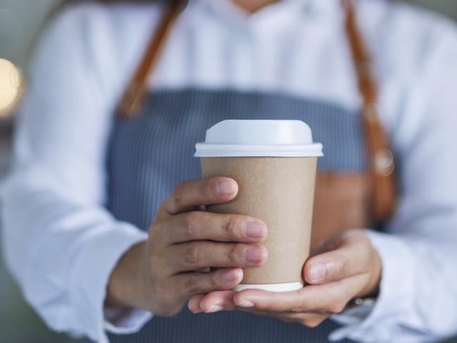 A waitress holding and serving a paper cup of hot coffee in cafe