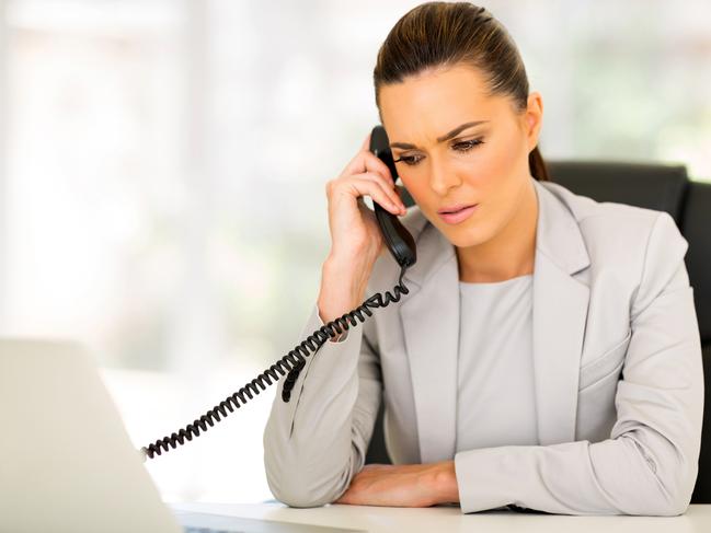 An attractive woman sitting on her desk and she is on the phone to her bank to discuss her home loan. Picture: iStock.