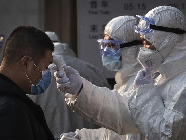 Chinese health workers check people entering a subway station during the Chinese New Year and Spring Festival in Beijing. Picture: Kevin Frayer/Getty Images