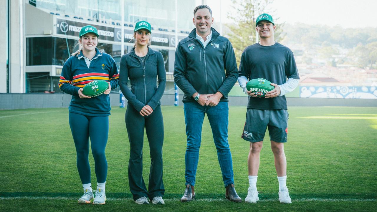 Business consumer manager Jesse O'Hara with three of the Tasmania Devils young members as it was announced the club will hit 210,000 members this week. Picture: AFL Tasmania