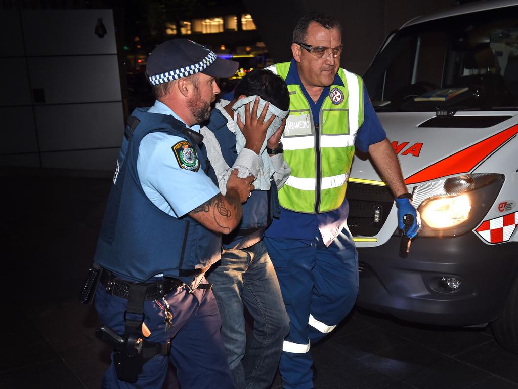 A policeman and paramedic escort a hostage away from the scene. Picture: William West (AFP)