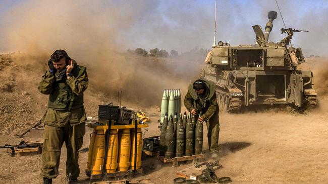 An Israeli army soldier covers his ears as a self-propelled artillery howitzer fires rounds from a position near the border with the Gaza Strip in southern Israel on Monday. Picture: AFP