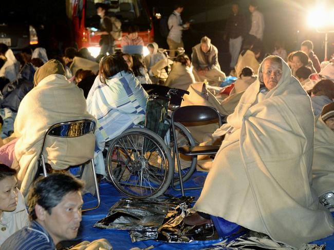 People wrap themselves in blankets as the residents take shelter outside the town hall of Mashiki, near Kumamoto city, southern Japan. Picture: AP