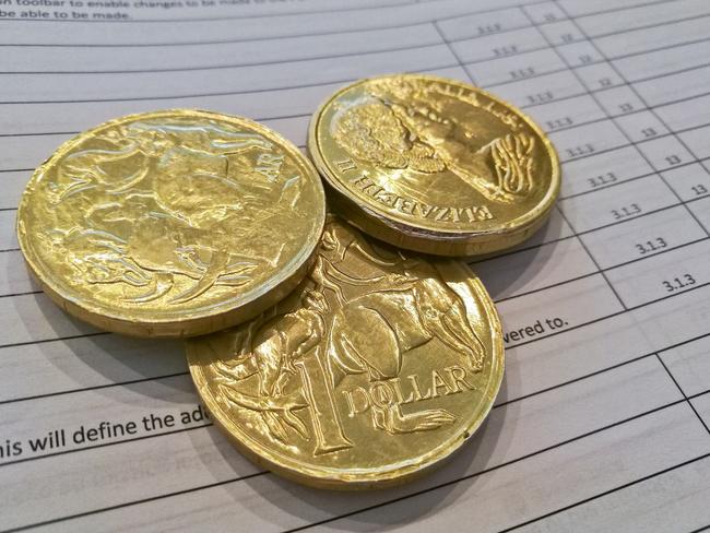 Three gold coins of Australian dollars on invoice sheet. Generic money cash