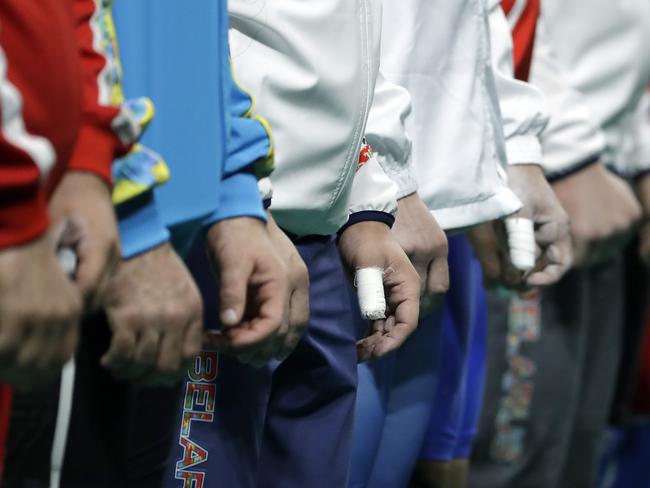 Weightlifters wait with taped hands as they are introduced before the start of the men's 85kg weightlifting competition at the 2016 Summer Olympics in Rio de Janeiro, Brazil, Friday, Aug. 12, 2016. (AP Photo/Mike Groll)