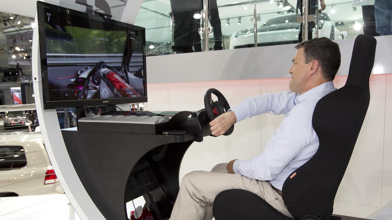 Former racing-car driver Neil Crompton competing in the 24-Hour Gran Turismo 5 Challenge, featuring a virtual recreation of Toyota's FT-86G Sports Concept motor car. The real-world motor car is at the top of the image - on Toyota's stand at the Australian International Motor Show.